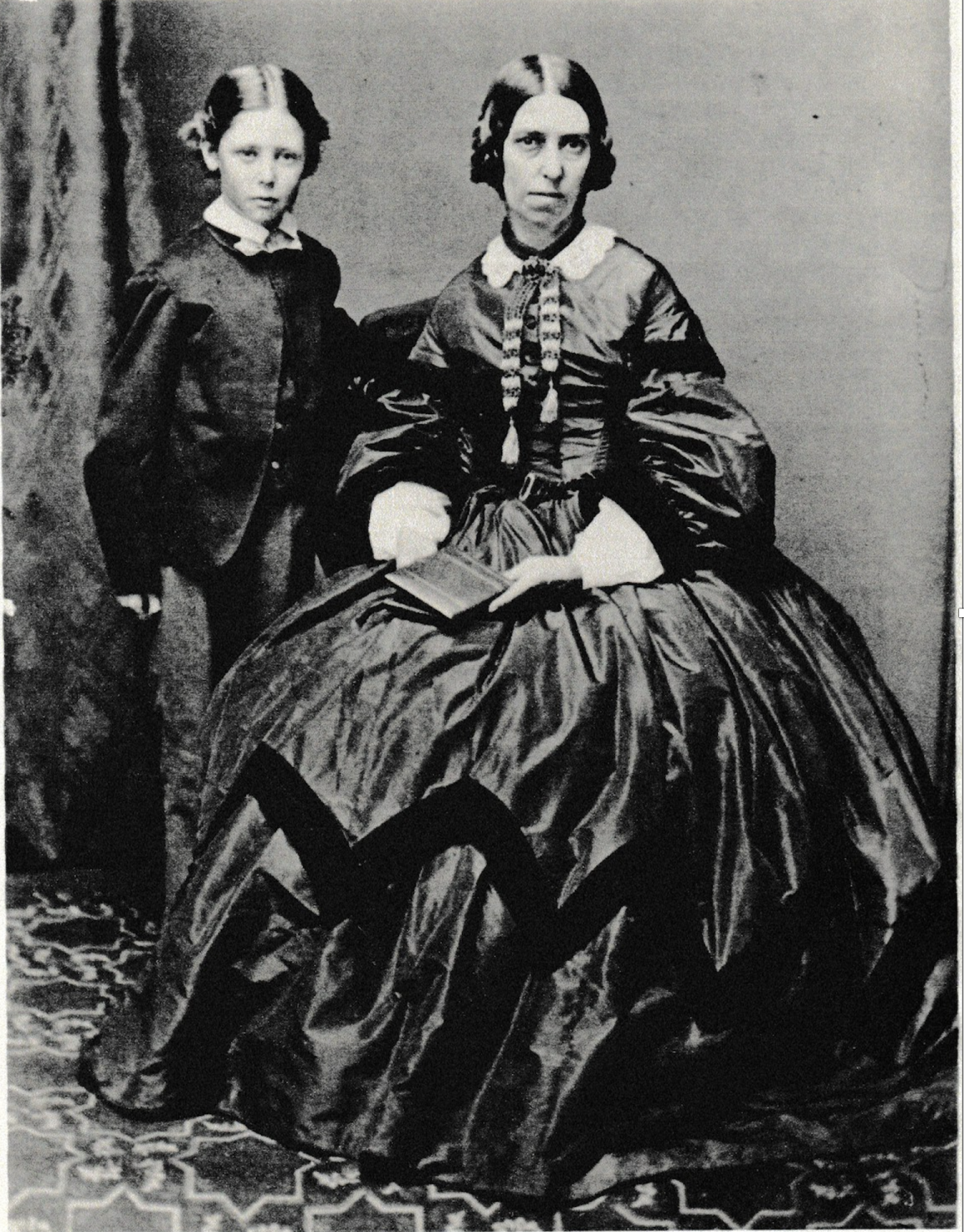 Portrait of mother and son, likely around ten years old, in dark clothes with serious expressions