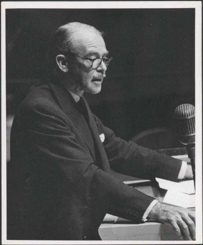 black and white photo of a man speaking at a lecturn