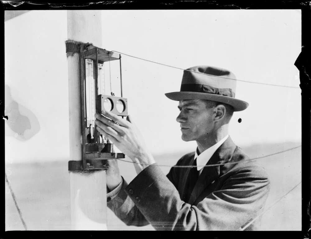 black and white photo of a man in a suit reading thermostats