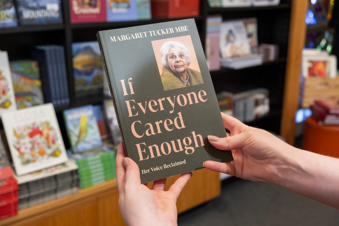 'If Everyone Cared Enough' by Margaret Tucker MBE, a book with a green cover with an image of Margaret Tucker, being held up in the Bookshop