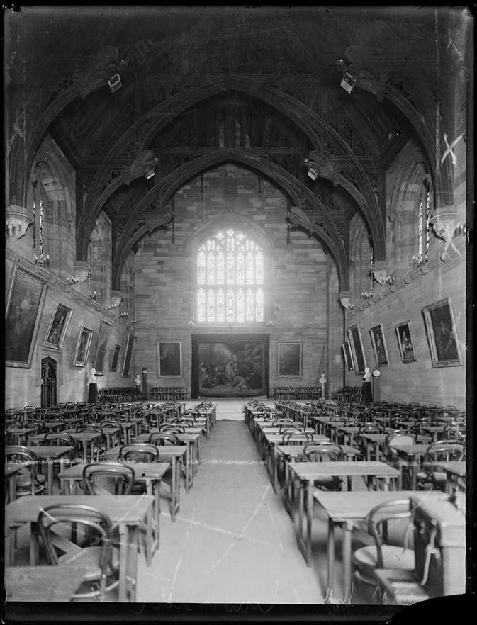 black and white photo of an study hall with desks and chairs but no people