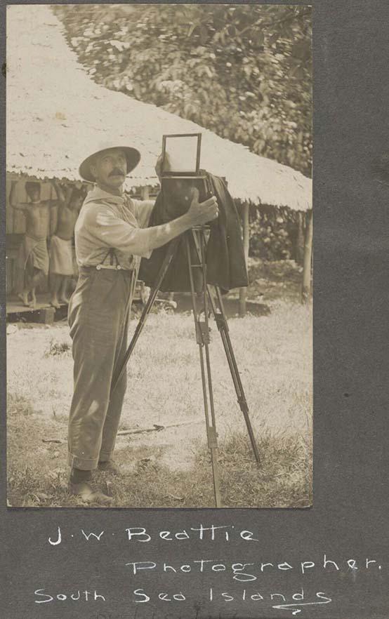 sepia-toned photo of a man with an old camera set up on a tripod