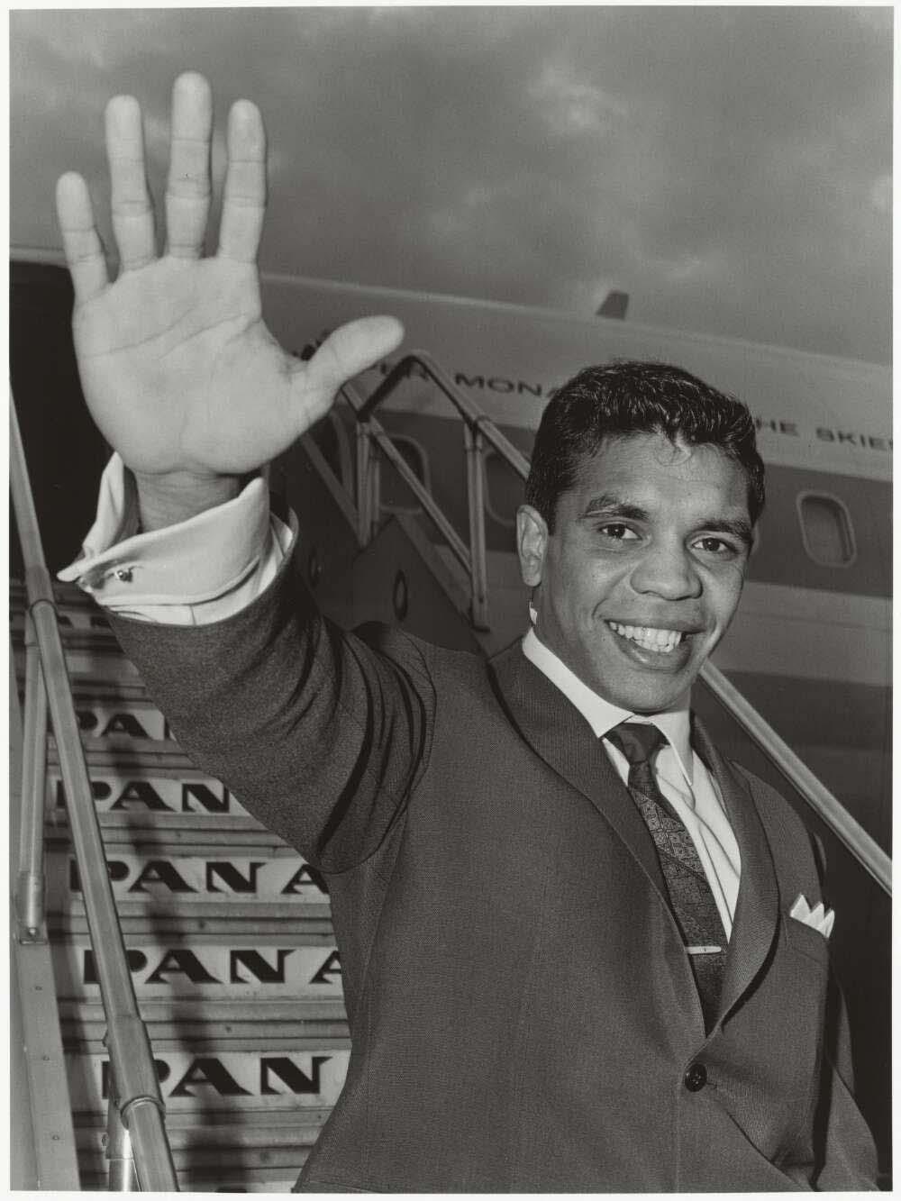 Black and white photo of Lionel Rose waving from the steps of a Pan Am plane in 1968