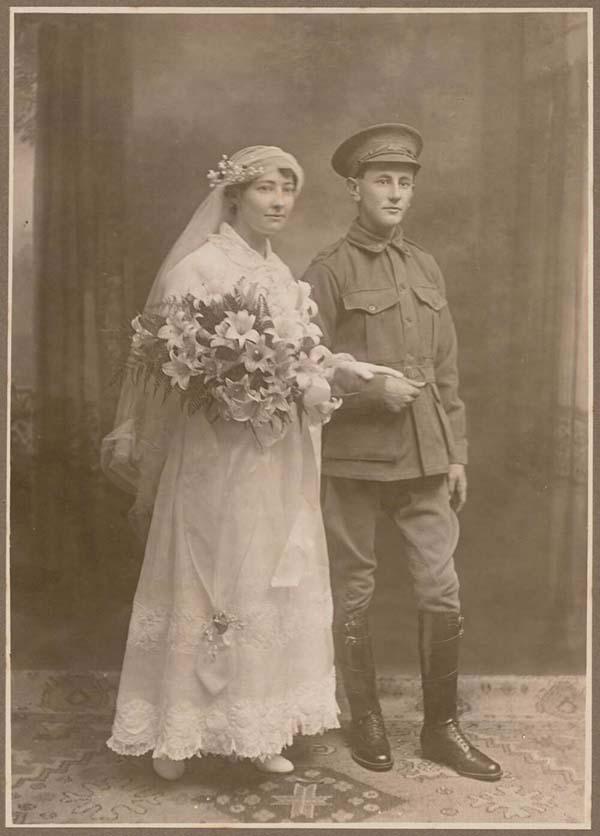 sepia photo of a man in army uniform and a woman in a white wedding dress holding a bouquet of flowers