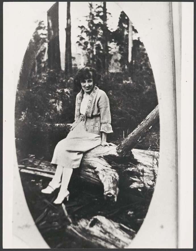 black and white photo of a woman sitting on a fallen log