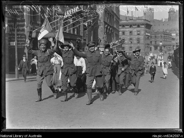 photo of soldiers waving flags and cheering as they walk down a street