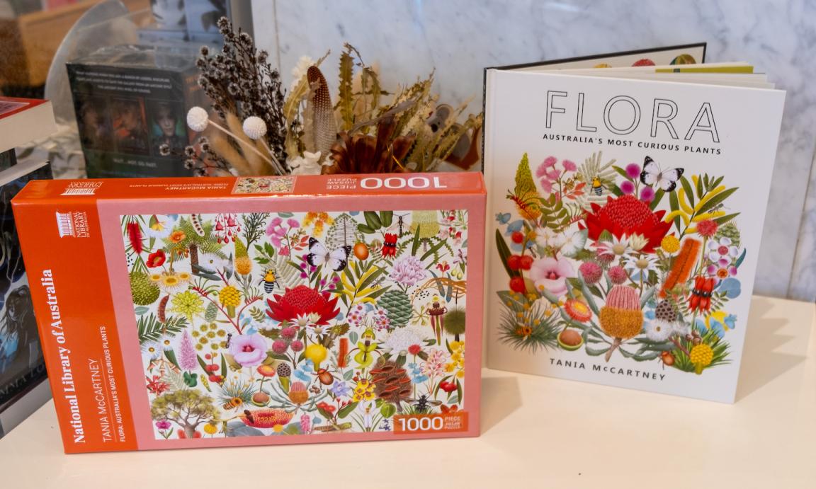 'Flora' by Tania McCartey book and related puzzle stood next to a vase of dried flowers