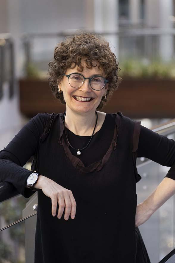 woman leaning against glass partition smiling at camera