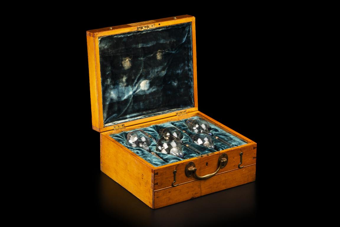 Glass x-ray bulbs/tubes laid on teal velvet in a wooden box