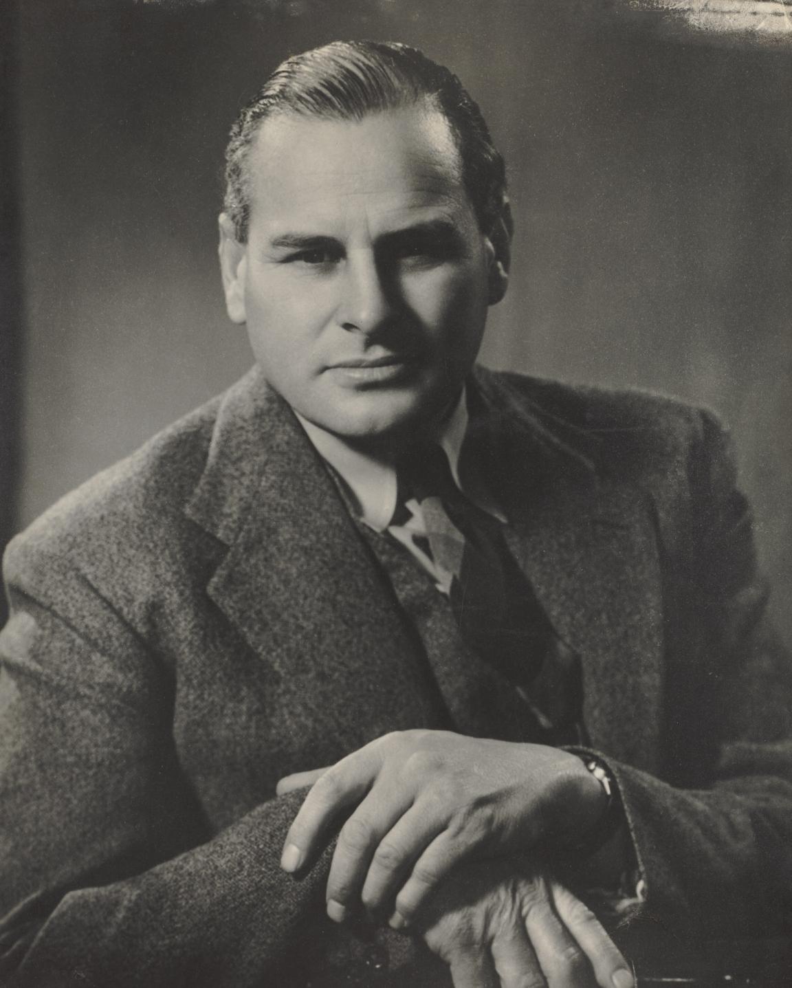 A posed black and white photographic portrait of Chester Wilmot looking at the camera