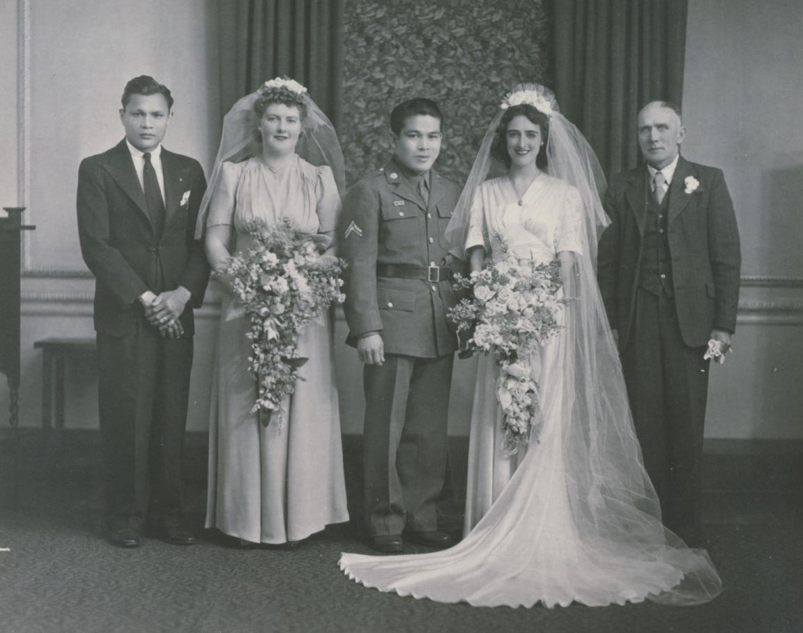 Black and white photo of groom Lorenzo Gamboa, in military dress, and bride Joyce Cain, wearing a short-sleeved white dress, along with two two men and a woman.