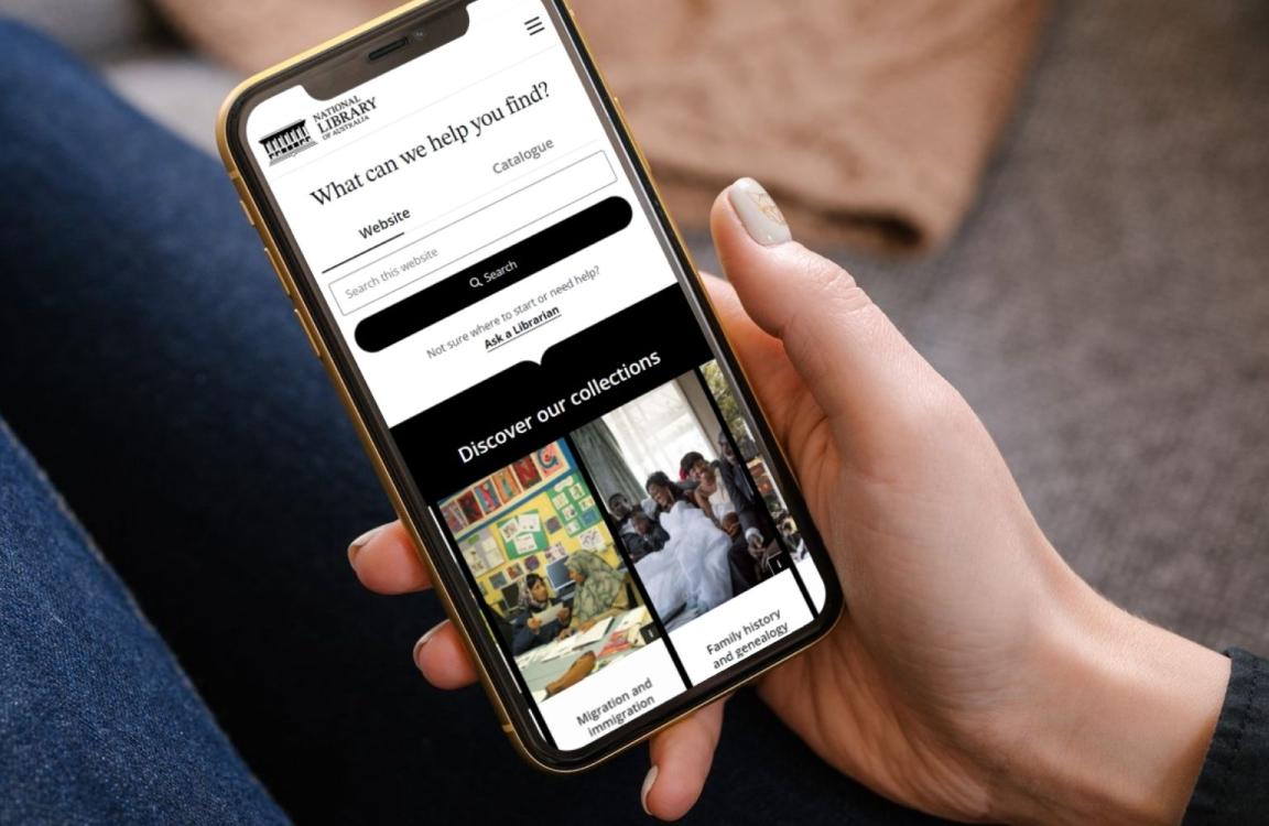 Hand holding a mobile phone open to the Library website homepage