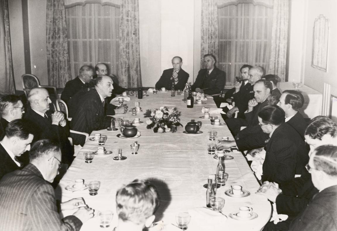 Several men in suits sitting around a dinner table