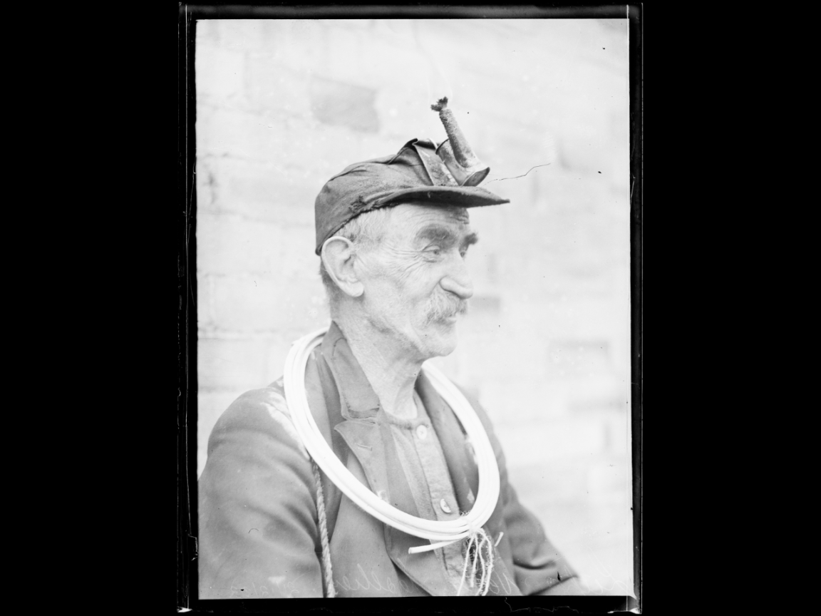 Black and white photo of a older man wearing an old-fashion at lamp