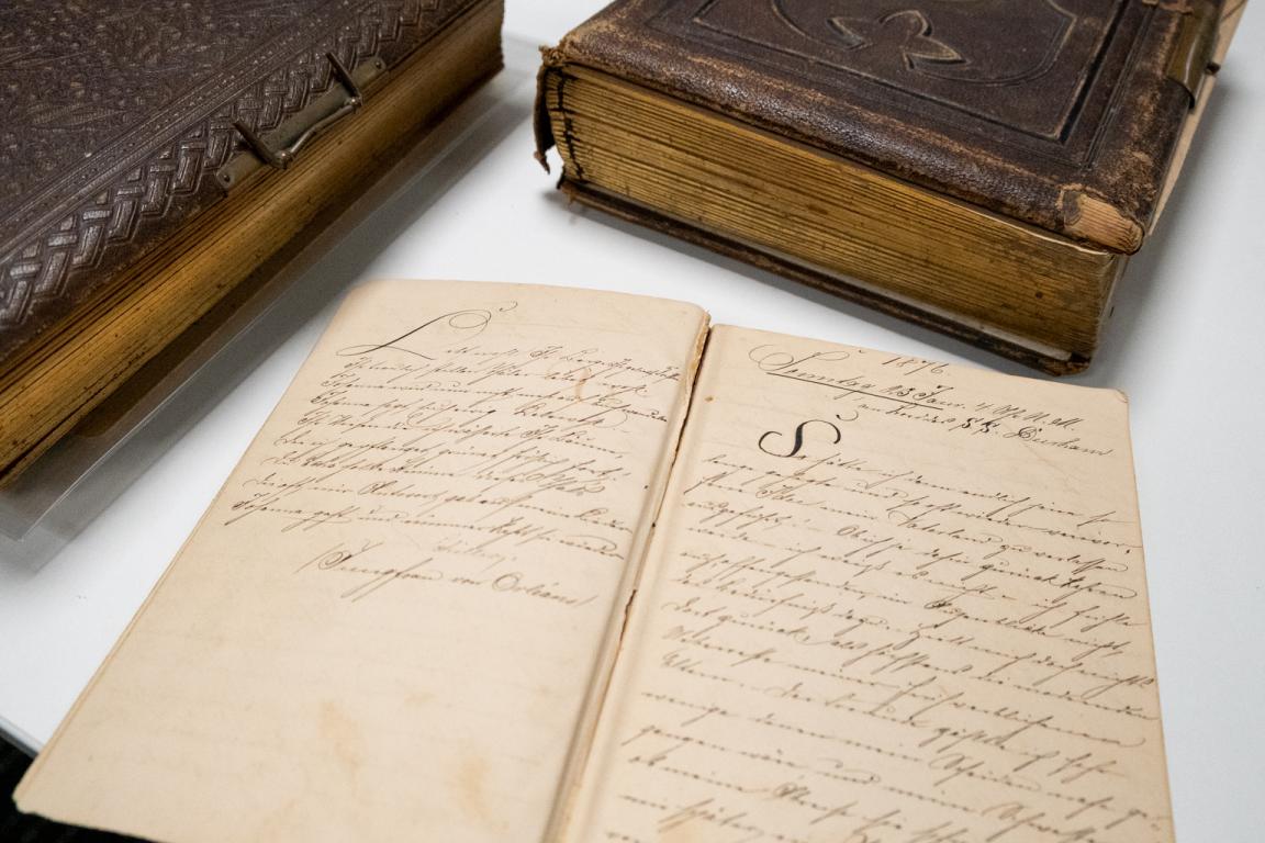 Three leatherbound diaries from the nineteenth century, one open showing neat handwriting