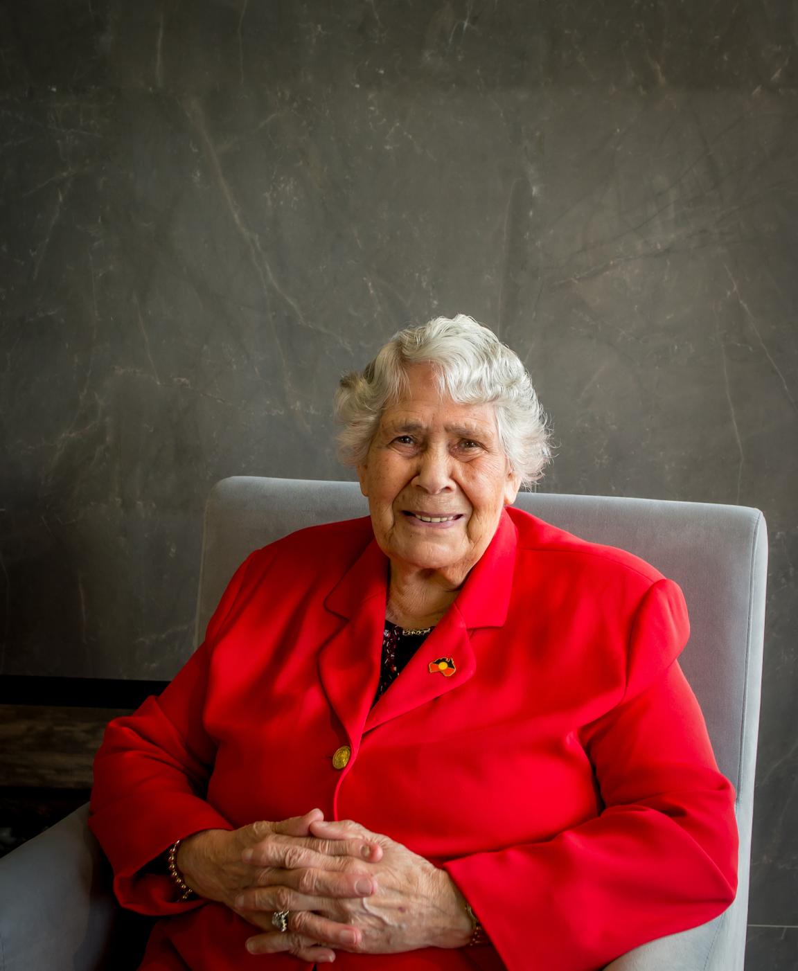 Dr Lowitja O'Donoghue sitting in an armchair and smiling