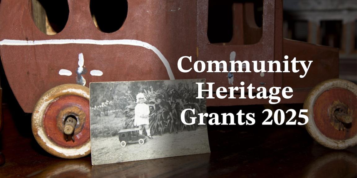 Black and white photo of a child with a toy car, leaning against the real toy car. On the right is white text reading 'Community Heritage Grants'