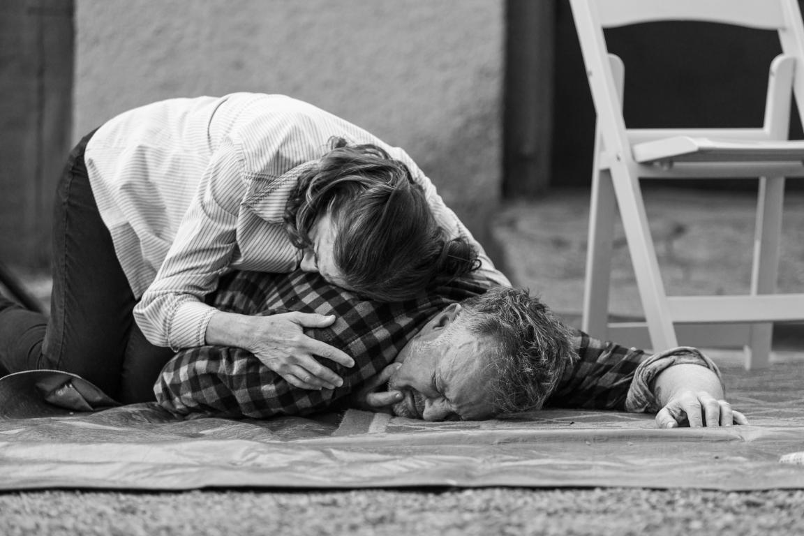 Man lying on the floor with a woman leaning over him hugging his shoulder