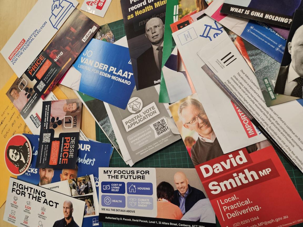 A variety of recently donated 2025 election campaign material laid out on a table. 
