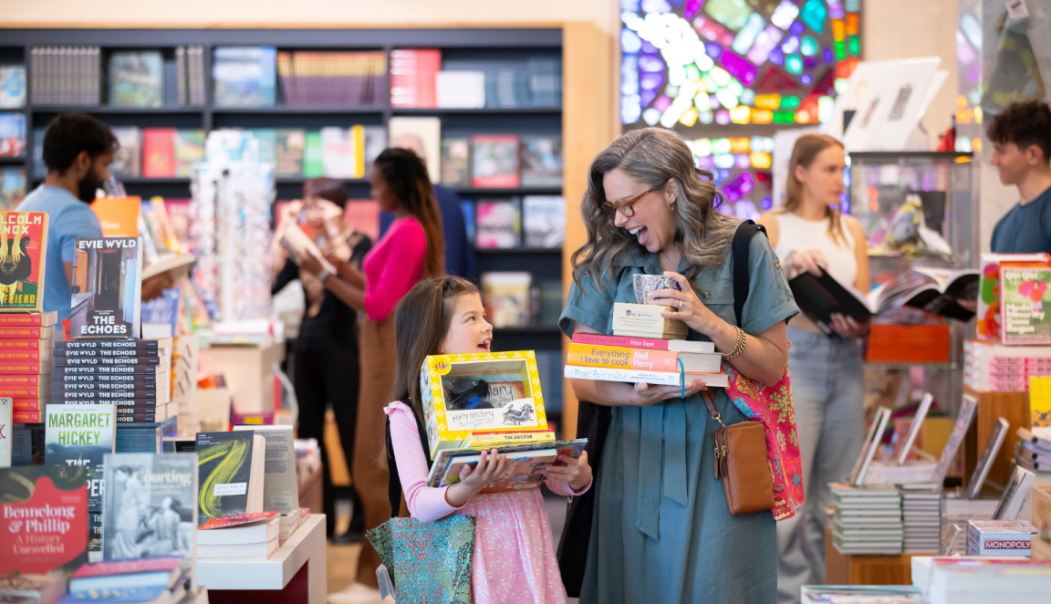A woman and child holding books and gifts in the National Library Bookshop.