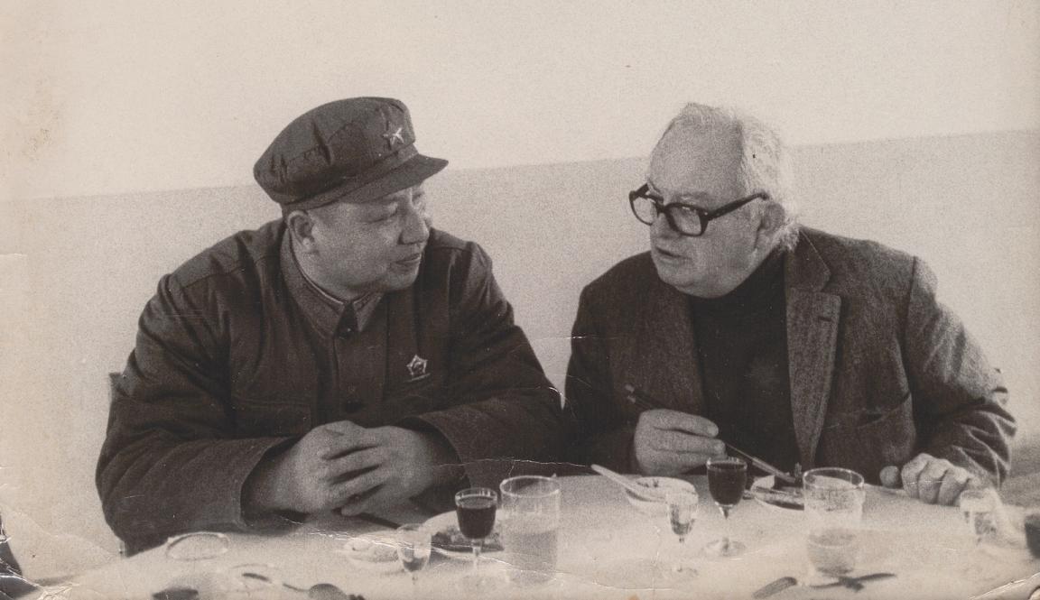 Two men, Wilfred Burchett and Mao Zedong sitting at a small table and talking over a meal