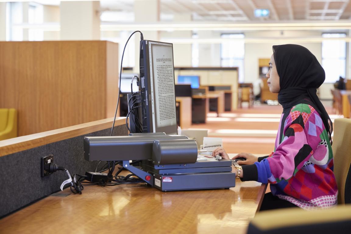 Dr Rafiqa Qurrata A'yun sitting and working at a computer in the Main Reading Room