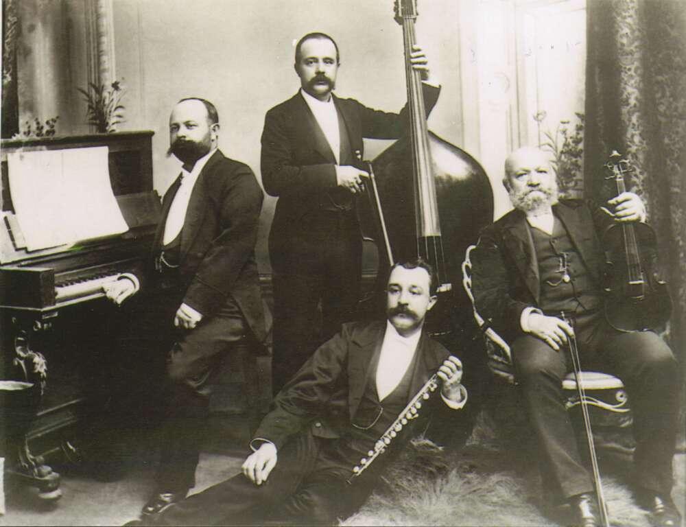 Four men posing in dress suits holding musical instruments.