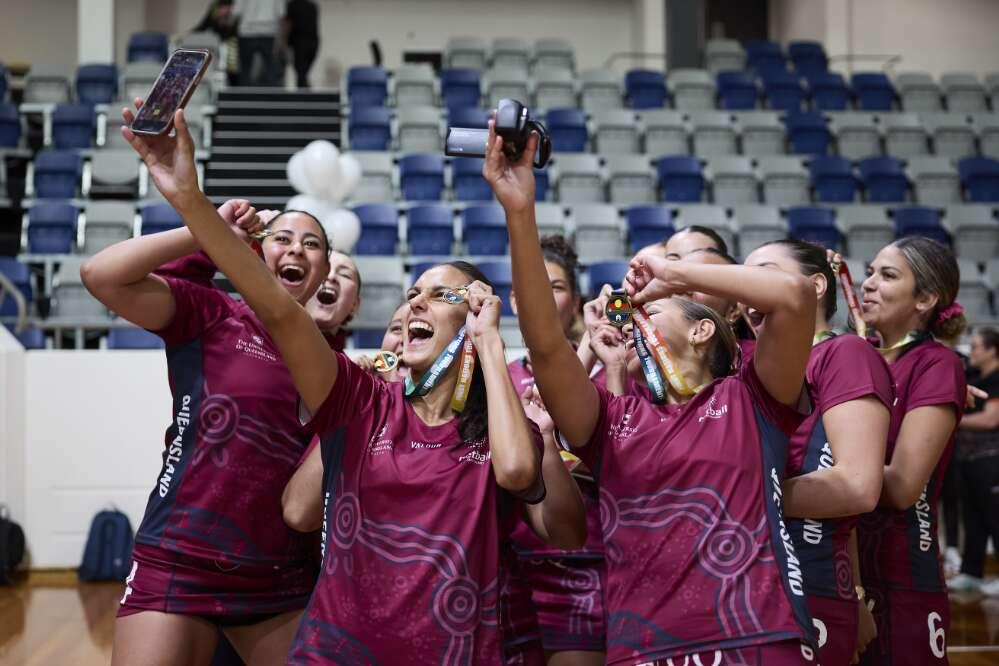 Team of female netball players taking a selfie with their winning medals