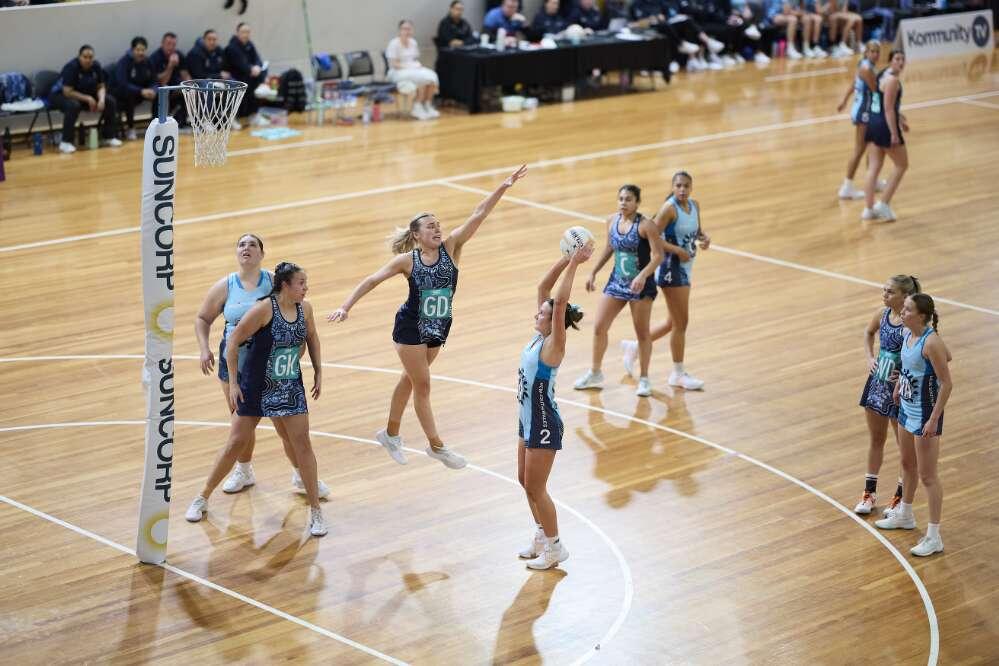 Action shot during a netball game as a women jumps up to prevent another from scoring