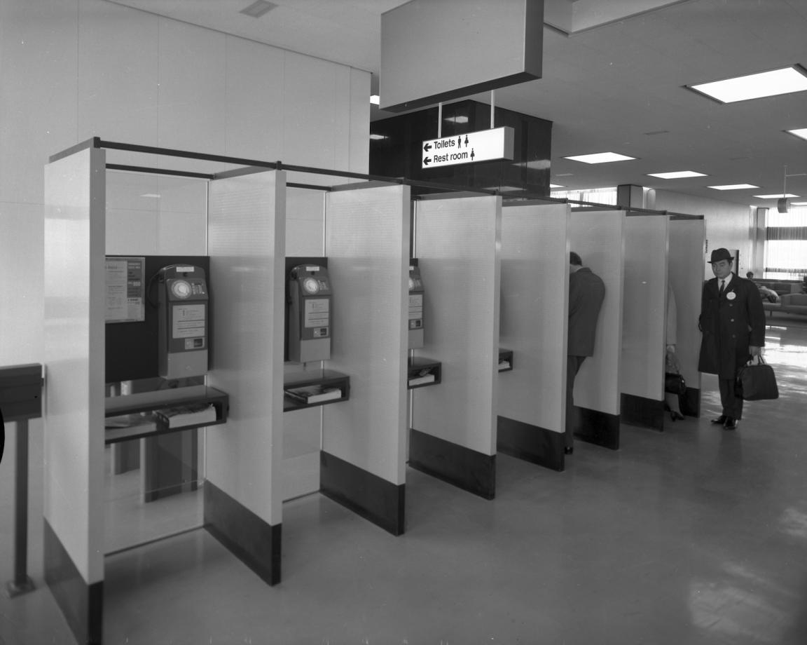 A black and white photograph of a row of public telephone booths at the Sydney International Airport