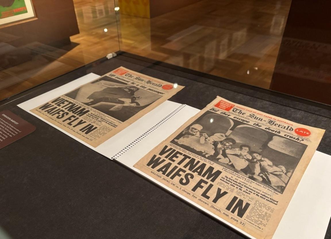 Two newspaper front covers in a display case. The headline on both reads, 'Vietnam waifs fly in'.
