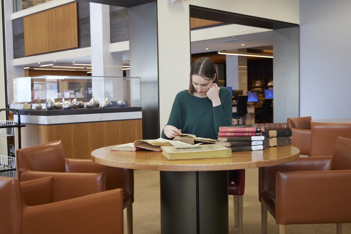 Dr Jorien van Beukering sitting at a desk reading collection material about Indonesia 