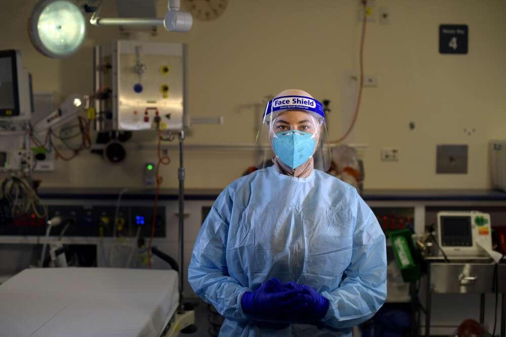 A nurse wearing full personal protective equipment standing in a hospital room