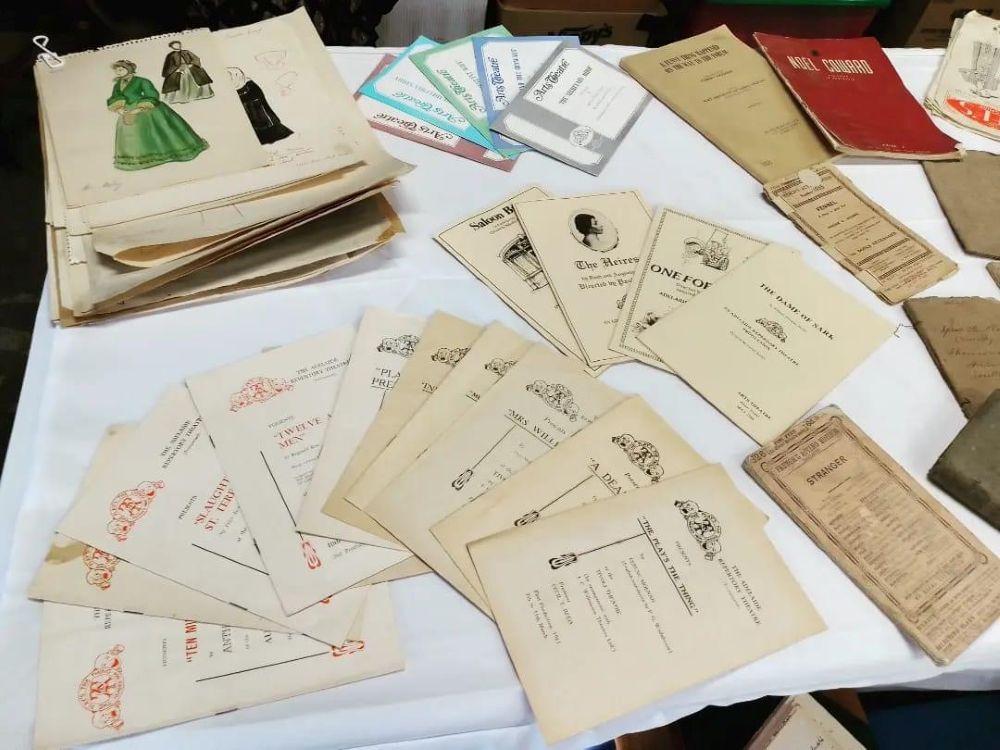 Theatre programs and costume drawings spread out on a table.