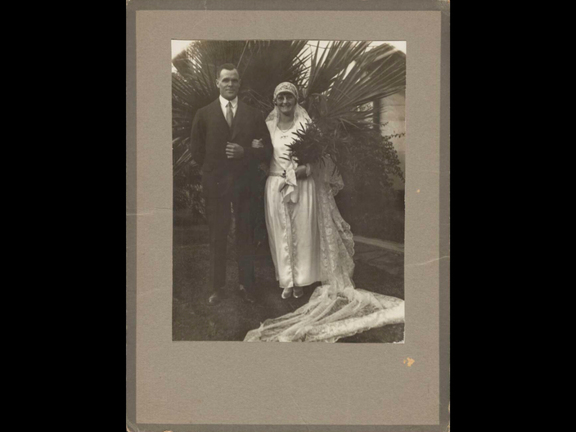 A man and woman pose for their wedding portrait in this image. The man is on the left hand side and the woman, the first to wear the Lockhart family’s wedding veil, is on the right. 