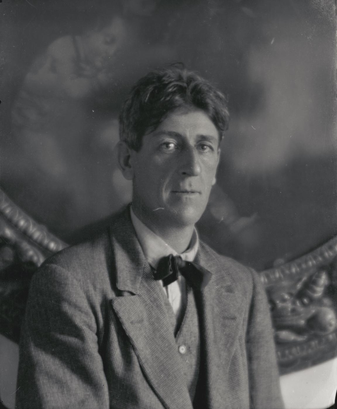 Black and white photo of William Hardy Wilson sitting in front of a large framed pianting