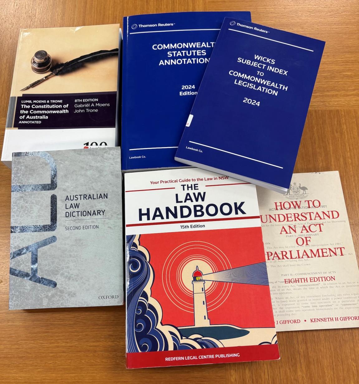 Six books about Australian legislation spread on a wooden table