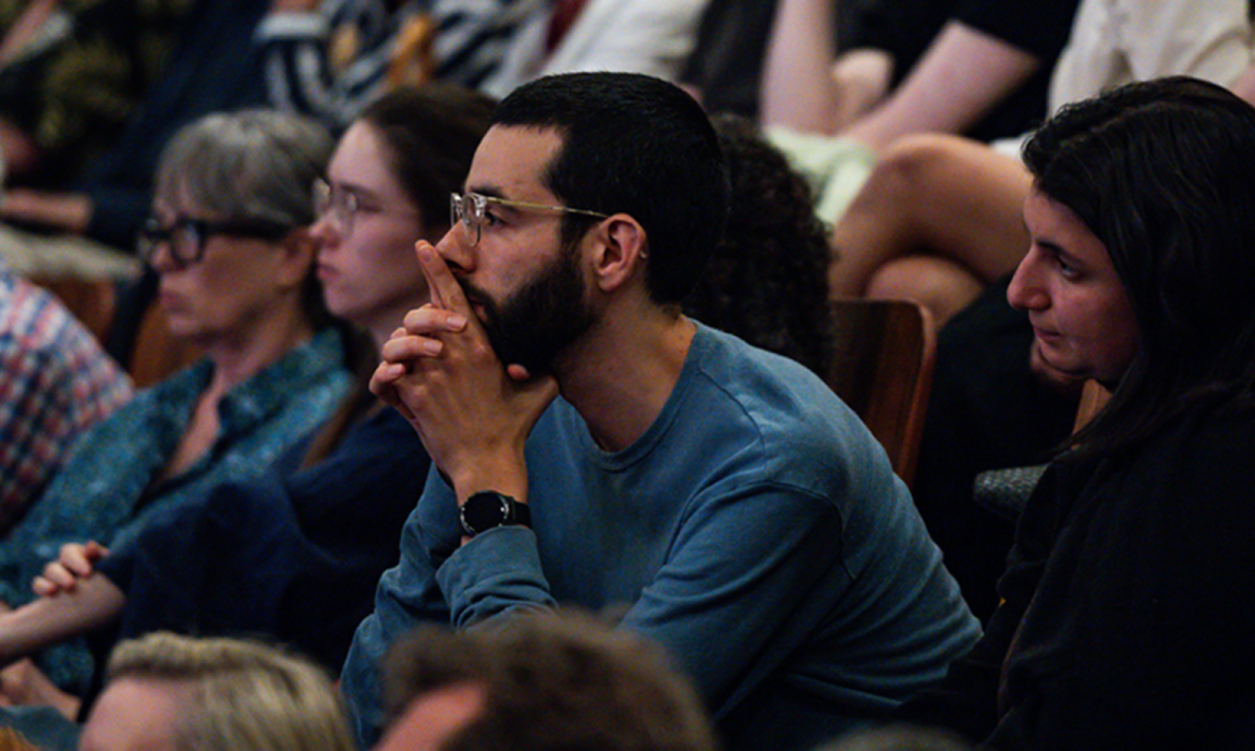 An audience watching a performance in a theatre with a focused expression