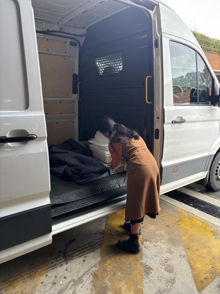A person places a boxed item into a white van.