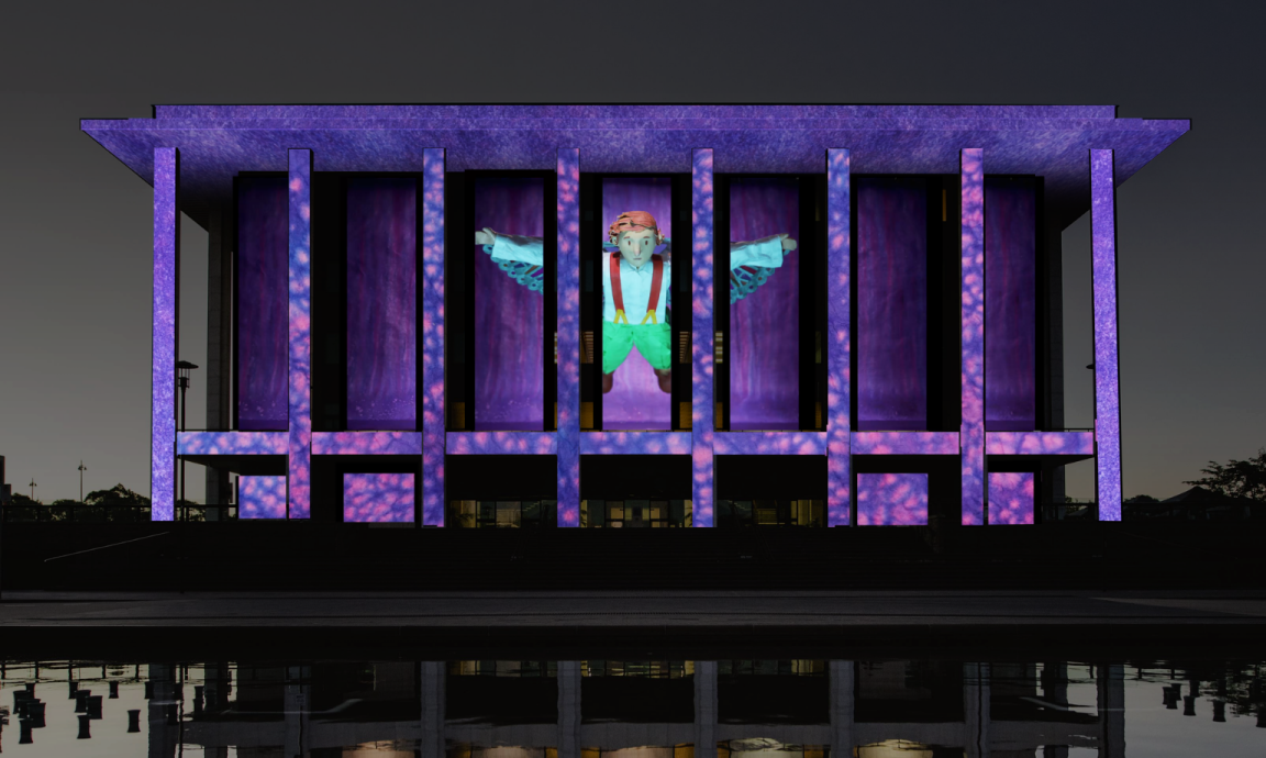 An illumination of the National Library of Australia building, showcasing a figurine with wings