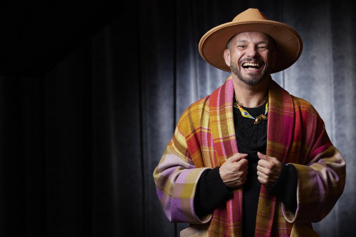Person in a colourful shawl and large hat laughing