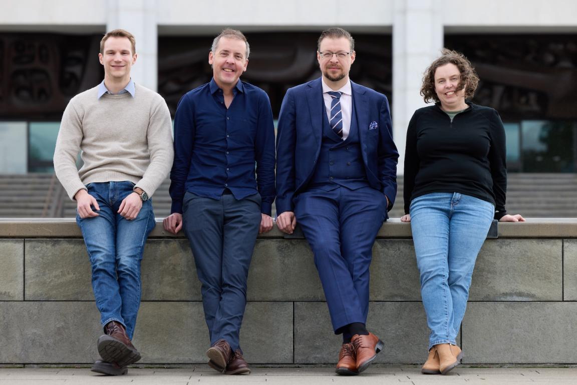 Three men and one woman standing in front og the National Library building