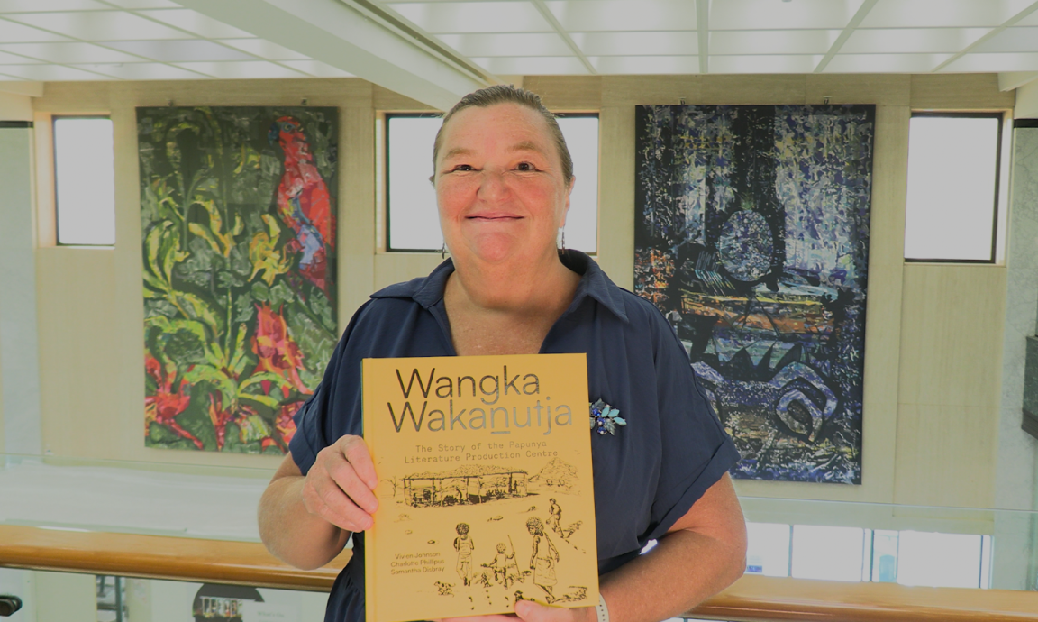 Rebecca Bateman, holding the NLA Publication, Wangka Wakanutja, in the National Library of Australia