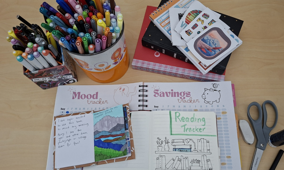 A planner featuring mood, reading and savings trackers with other stationary items on display like pens, eraser, scissors and glue