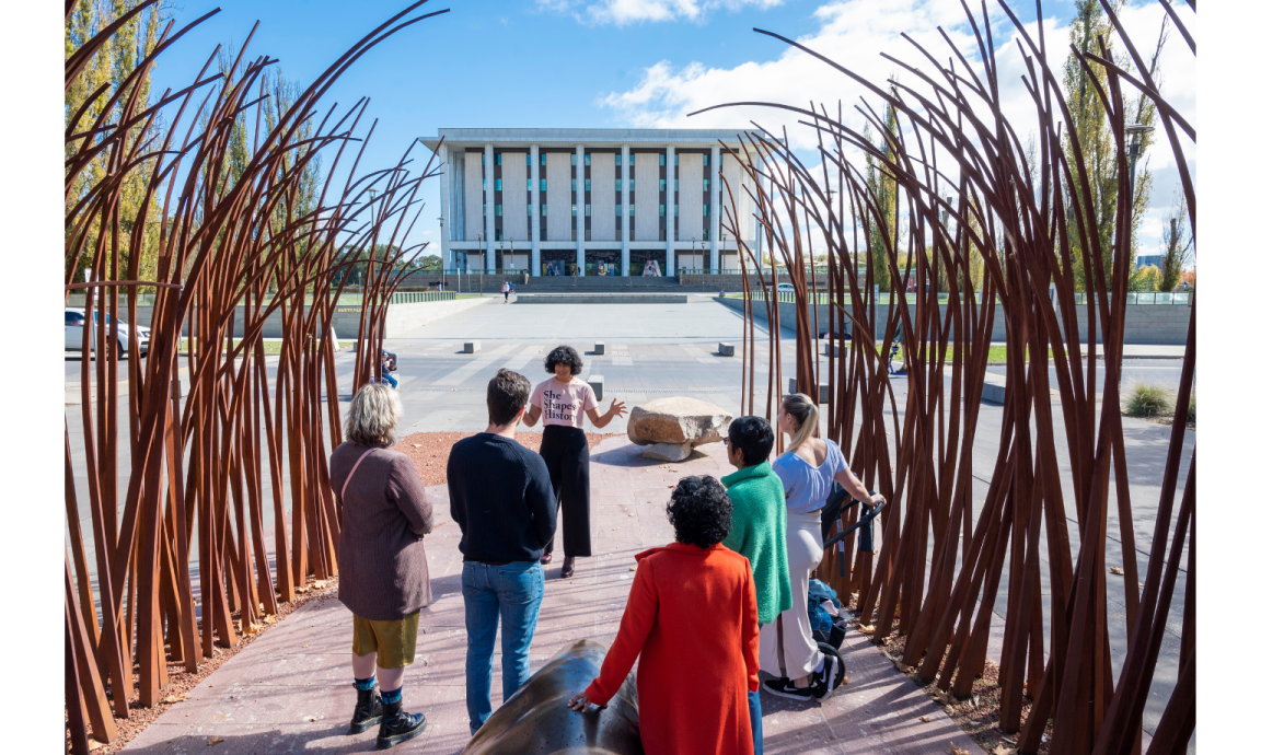 Sita Sargeant standing before a group across the road of the front of the National Library of Australia