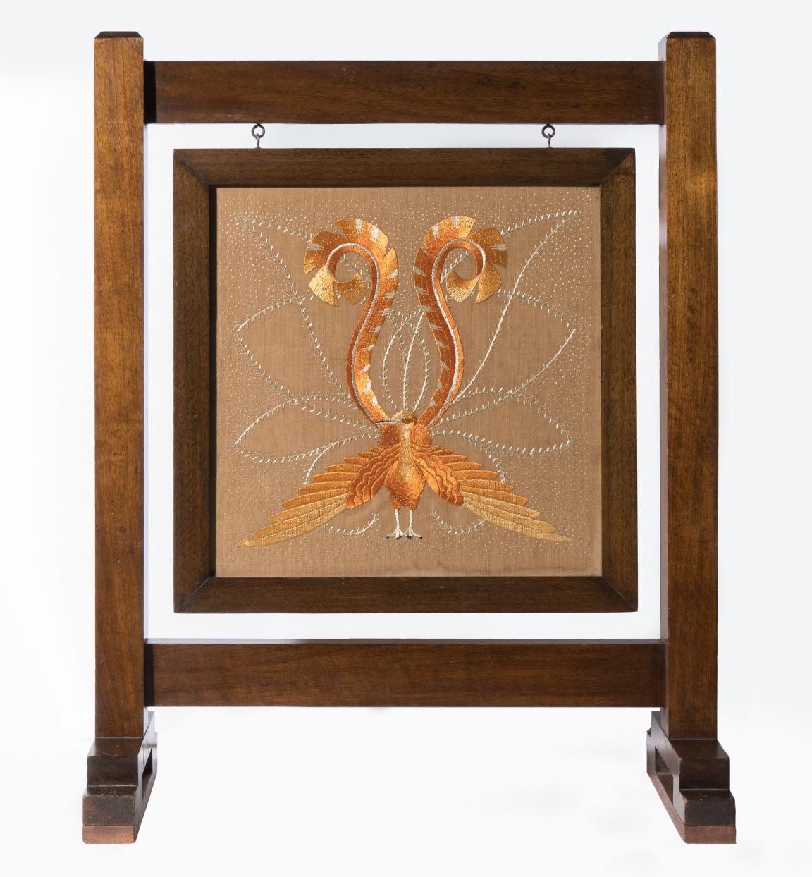 A handcrafted timber fireplace screen with a lyrebird tapestry hung in the centre of a frame