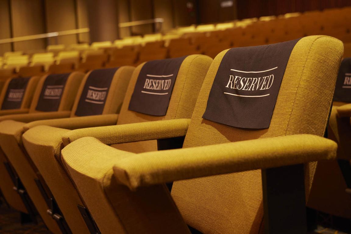 A row of empty theatre seats with 'reserved' signs