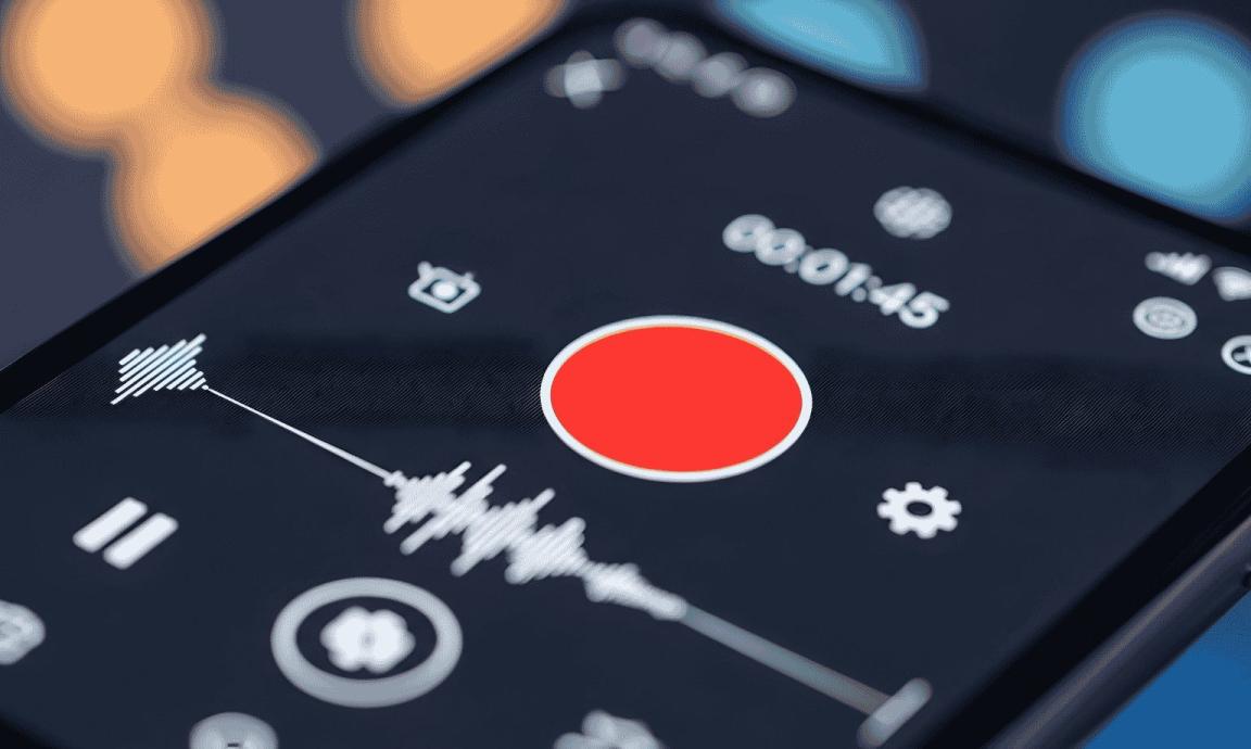 A smartphone with the recording screen on with a red record button and soundwaves.