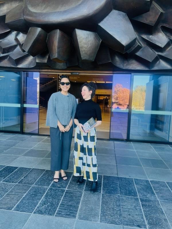 Two women standing in front of the front entrance of the National Library