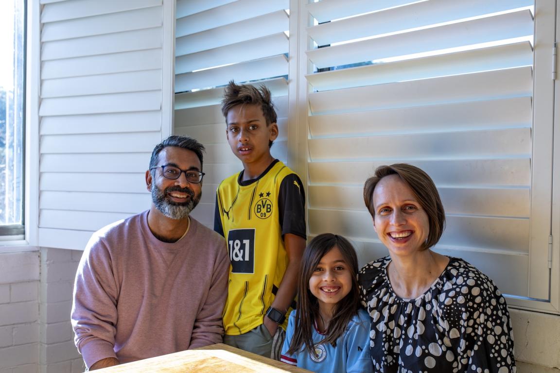 Indian-Australian family, made up of a mother, father, a young son and young daughter, smiling at the camera